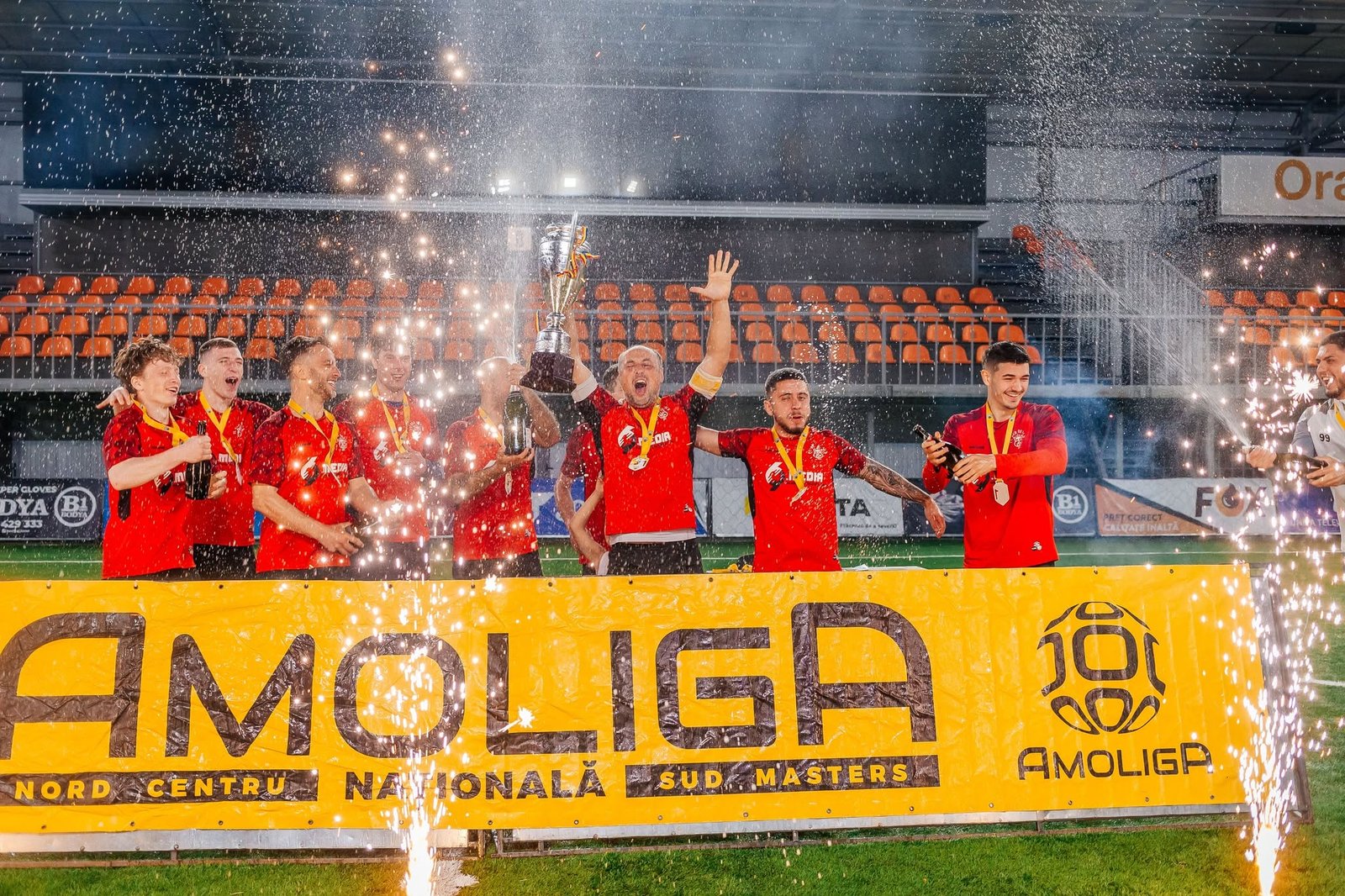 FC Red Devils players lifting the 2025-2026 AMOLIGA Centru champions trophy while wearing shirts with the 69 Media sponsor logo